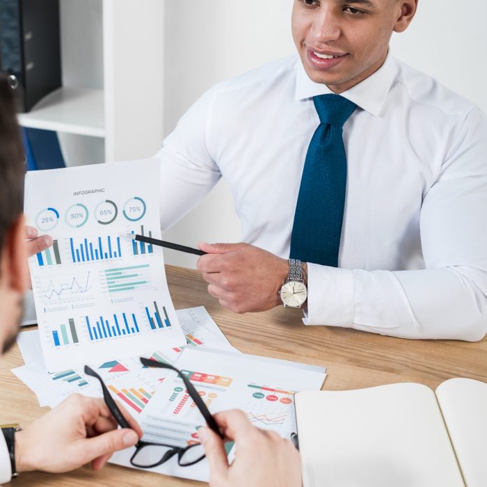 close-up-smiling-young-businessman-showing-graph-with-pencil-his-business-partner-workplace close-up-smiling-young-businessman-showing-graph-with-pencil-his-business-partner-workplace